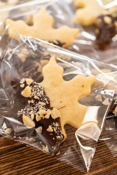 stock image Carefully packaging Christmas cutout cookies, half-dipped in chocolate and presented in clear cellophane wrapping, perfect for festive gifting.