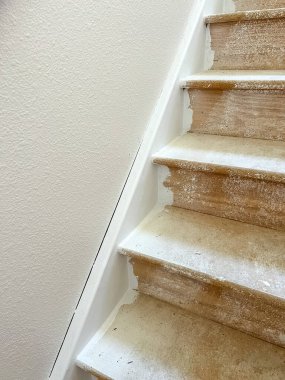 Tamamlanmamış basamakları ve duvar onarımlarını gösteren, yenilenen bir merdivenin detaylı bir yakın plan görüntüsü. Basamaklar inşaat tozu ile kaplı ve duvarın bazı kısımları gözle görülür şekilde işaretlenmiş.
