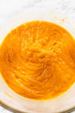 Ağız sulandırıcı ev yapımı balkabağı pastası için büyük bir karıştırma kabında ustalıkla harmanlanmış malzemelerin yakın çekimi..