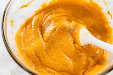 Ağız sulandırıcı ev yapımı balkabağı pastası için büyük bir karıştırma kabında ustalıkla harmanlanmış malzemelerin yakın çekimi..