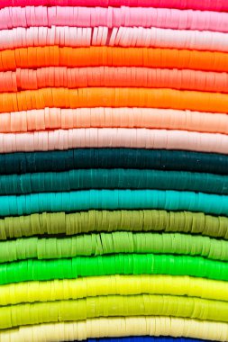 Beyaz bir masadaki renklere göre düzenlenmiş canlı bir kil boncuk koleksiyonu genç zanaatkarlara kendi eşsiz bileziklerini yapmaları için ilham vermeye hazır..