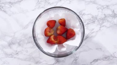 Çilekler, yeni yıkanmış ve kurutulmuş, cam bir kasede güzelce depolanmış kağıt havluyla kaplanmış ve tazeliği korumak için plastikle kaplanmış..