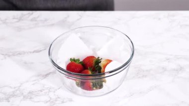 Çilekler, yeni yıkanmış ve kurutulmuş, cam bir kasede güzelce depolanmış kağıt havluyla kaplanmış ve tazeliği korumak için plastikle kaplanmış..