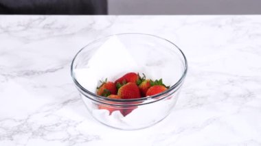 Çilekler, yeni yıkanmış ve kurutulmuş, cam bir kasede güzelce depolanmış kağıt havluyla kaplanmış ve tazeliği korumak için plastikle kaplanmış..