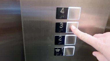 Bu görüntü, bir oteldeki asansör kontrol panelini yakılmış düğmeleri kırmızı düğmeyle göstererek aktif seçilimi gösterir..