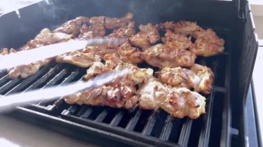 Salamura edilmiş tavuk butları küçük bir Weber ızgarasının ızgarasında cızırdar, havayı iştah açıcı bir koku ve hafif bir dumanla doldurur..