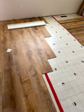 This image depicts the process of installing new laminate flooring over an underlayment. The partially installed laminate planks and the underlayment grid layout are clearly visible, demonstrating the clipart