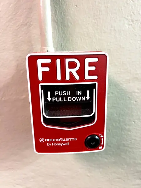 stock image Denver, Colorado, USA-July 12, 2024- The image showcases a close-up view of a red fire alarm pull station mounted on a wall. The fire alarm, by Honeywell, prominently displays the instructions PUSH IN