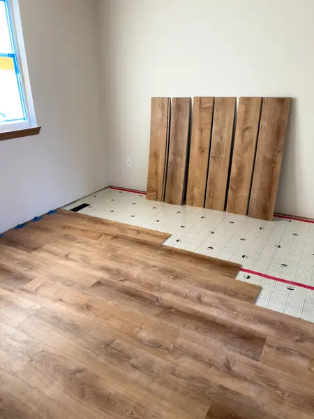 stock image Broomfield, Colorado, USA-July 13, 2024- This image depicts the process of installing new laminate flooring over an underlayment. The partially installed laminate planks and the underlayment grid