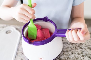 Hevesli gözler canlı çömleğe odaklanmış, eriten şekerler genç bir aşçı karışımı nazikçe kıvırıyor, sade atıştırmalıkları lezzetli yiyeceklere dönüştürmeye hazırlanıyor..