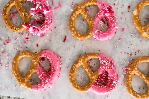 stock image Freshly dipped and still glistening, these crunchy pretzels are lovingly adorned with pink chocolate and a scattering of colorful sprinkles, promising a feast for the senses.