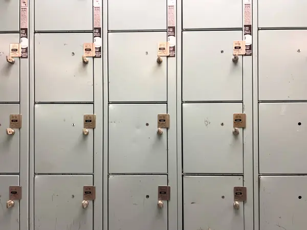 stock image Denver, Colorado, USA-July 12, 2024-A row of metal lockers in a locker room, complete with combination locks and benches for seating. The lockers show signs of use, adding character to the space, and