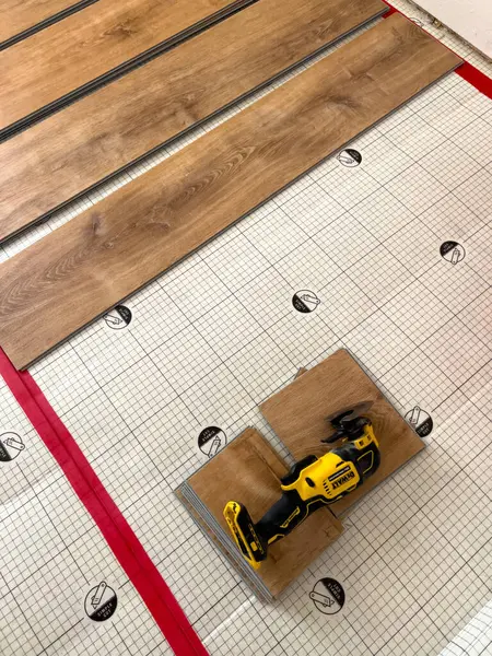 stock image Broomfield, Colorado, USA-July 7, 2024-Close-up of vinyl planks and a Dewalt power tool on top of underlayment, ready for installation. The photo shows essential materials and tools for laying vinyl