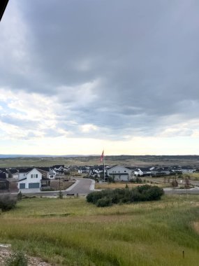 Castle Rock, Colorado, ABD-6 Temmuz 2024 banliyö manzarası evleri ve bayrak direği olan bir banliyö mahallesi, kayan tepeler ve bulutlu bir gökyüzüne karşı kurulmuş. Yeşil alanlar ve açık alanlar