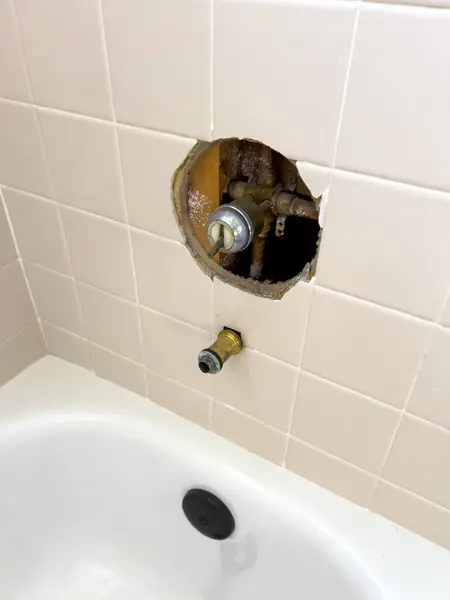 stock image Broomfield, Colorado, USA-July 6, 2024-A close-up view of a bathroom plumbing repair in progress. The wall tiles above the bathtub are removed to expose the plumbing fixtures, indicating maintenance