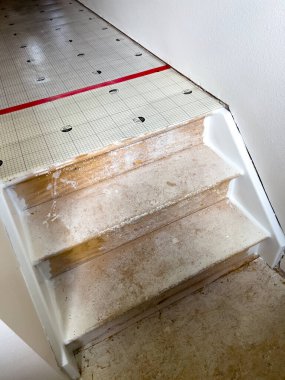 Broomfield, Colorado, USA-July 6, 2024-A staircase in the midst of renovation, with paper covering the handrail and stairs. The living room area shows windows taped for painting and several toolboxes clipart