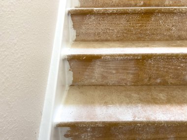 Yakın plan görüntü, merdiven inişinde ahşap kaplama döşeme kurulumunun ilerlemesini gösteriyor. Üst basamak yeni kaplama döşeme ile kaplıyken, alt basamaklar ve çevre alan