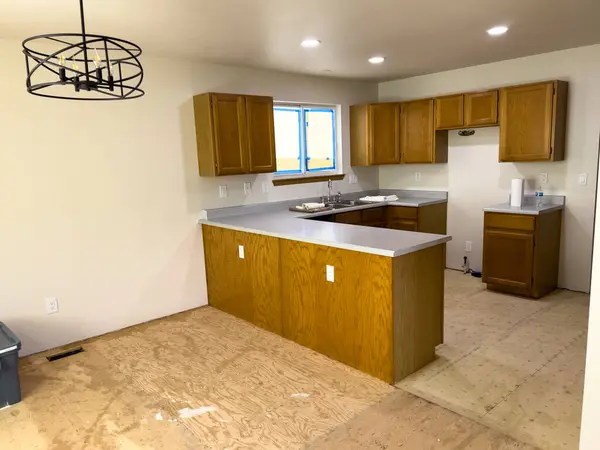 stock image Broomfield, Colorado, USA-July 6, 2024-A kitchen undergoing renovation, featuring wooden cabinets and an unfinished plywood floor. The countertops are installed, and the window is taped for painting