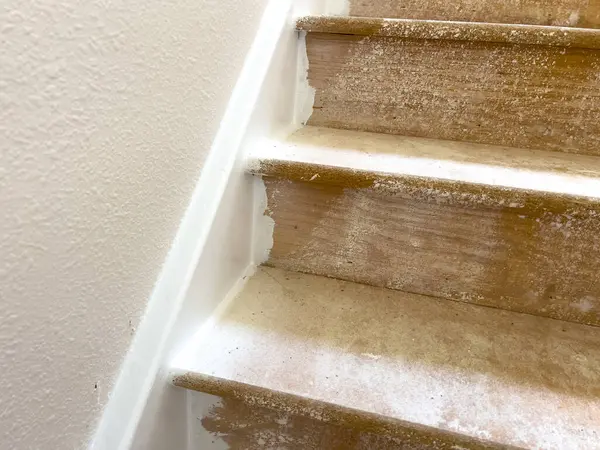 Stock image Close-up image showing the progress of wood laminate flooring installation on a staircase landing. The top step is covered with new laminate flooring, while the lower steps and surrounding area show