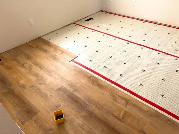 stock image Broomfield, Colorado, USA-July 6, 2024-A room in the process of flooring installation, showing a partially completed wooden floor with a section of underlayment visible. A small yellow storage bin