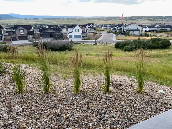 stock image Castle Rock, Colorado, USA-July 6, 2024-Scenic view of a suburban neighborhood with houses and a flagpole, set against a backdrop of rolling hills and a cloudy sky. The green fields and open spaces