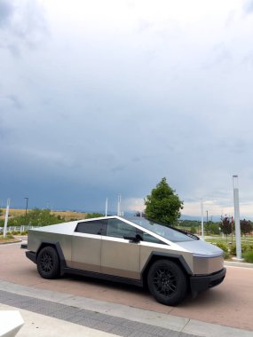 Denver, Colorado, ABD-17 Temmuz 2024 Sek Tesla Cybertruck bulutlu bir gökyüzünün arka planına park edilmiş durumda. Elektrikli aracın fütüristik, açısal tasarımı doğal olarak göze çarpıyor.
