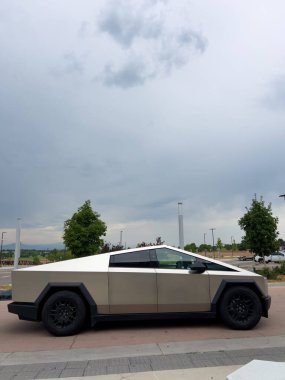 Denver, Colorado, ABD-17 Temmuz 2024 Sek Tesla Cybertruck bulutlu bir gökyüzünün arka planına park edilmiş durumda. Elektrikli aracın fütüristik, açısal tasarımı doğal olarak göze çarpıyor.