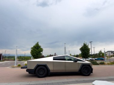 Denver, Colorado, ABD-17 Temmuz 2024 Sek Tesla Cybertruck bulutlu bir gökyüzünün arka planına park edilmiş durumda. Elektrikli aracın fütüristik, açısal tasarımı doğal olarak göze çarpıyor.