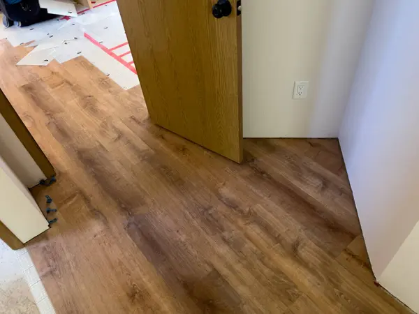 stock image Broomfield, Colorado, USA-July 6, 2024-A detailed view of the flooring installation process, showing wooden laminate flooring being laid over a grid-patterned underlayment. The underlayment is secured