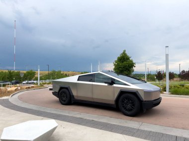 Denver, Colorado, ABD-17 Temmuz 2024 Sek Tesla Cybertruck bulutlu bir gökyüzünün arka planına park edilmiş durumda. Elektrikli aracın fütüristik, açısal tasarımı doğal olarak göze çarpıyor.
