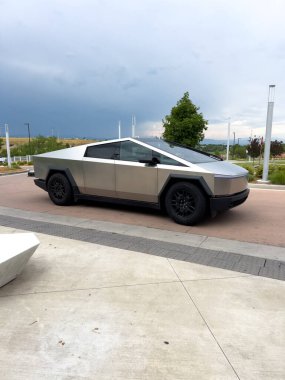 Denver, Colorado, ABD-17 Temmuz 2024 Sek Tesla Cybertruck bulutlu bir gökyüzünün arka planına park edilmiş durumda. Elektrikli aracın fütüristik, açısal tasarımı doğal olarak göze çarpıyor.
