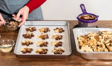 Çikolataya batırılmış ve fındık ezmesi ile süslenmiş kar tanesi şeklindeki kesme şekerli kurabiyeler yaratmak. Parşömen üzerinde zarif bir şekilde sunulmuş..