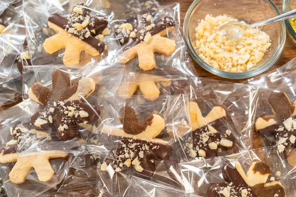 stock image Carefully packaging Christmas cutout cookies, half-dipped in chocolate and presented in clear cellophane wrapping, perfect for festive gifting.