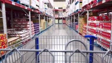 Denver, Colorado, ABD-28 Şubat 2024-Ağır çekim. Fotoğraf, Sams Club 'ın düzenli ve kapsamlı koridorlarında gezinen yüklü olmayan bir alışveriş arabasının içinden birinci şahıs görüntüsünü sunuyor.