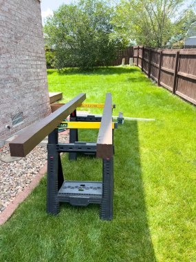 Süpürge, Colorado, ABD-20 Temmuz 2024. Çit direğinin tamiri için yakın çekim görüntüsü. Görüntü kısmen kaldırılmış bir tuğla patika yolu, bir çekiç ve çit direğinin yanına yerleştirilmiş bir levye gösteriyor.