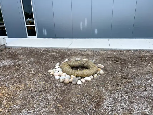 stock image This image depicts an outdoor drainage system protected by erosion control measures. The drain is surrounded by a circular barrier made of natural fiber rolls and large river rocks. The setup ensures