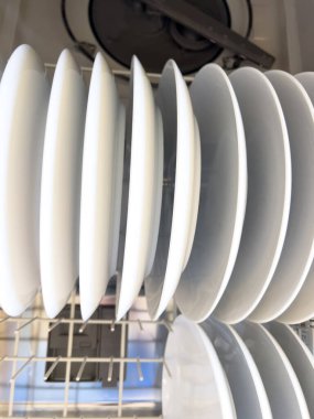 Bu resim temiz beyaz tabaklarla dolu bir bulaşık makinesini sergiliyor. Tabaklar üst rafa yerleştirilirken, tabaklar da üst rafa konur. Organize düzen gösteriyor ki...