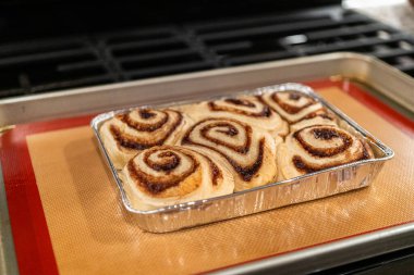 Fırından yeni çıkmış, tarçınlı çörek silikon bir hasırın üzerinde serinliyor, kremaları mutfak ışıklarının altında parlıyor..