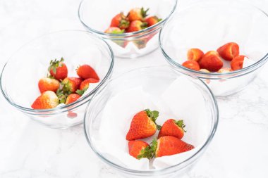 Taze yıkanmış ve kurutulmuş çilekler kağıt havluyla kaplı cam bir kasede dikkatlice düzenlenir. Atıştırmaya ya da daha fazla kullanılmaya hazır hale getirilir..