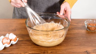 Bardak karıştırma kabında, büyük bir el çırpma ustalıkla lezzetli zencefilli kek ve karamel kremalı pasta malzemelerini karıştırır..