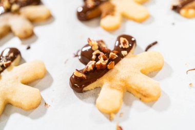 Çikolataya batırılmış ve fındık ezmesi ile süslenmiş kar tanesi şeklindeki kesme şekerli kurabiyeler yaratmak. Parşömen üzerinde zarif bir şekilde sunulmuş..