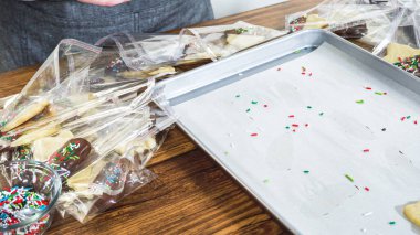 Dikkatlice paketlenmiş Noel kurabiyeleri, çikolataya batırılmış ve şeffaf selofan ambalajla sunulmuş, bayram hediyesi olarak mükemmel..