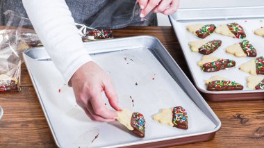 Dikkatlice paketlenmiş Noel kurabiyeleri, çikolataya batırılmış ve şeffaf selofan ambalajla sunulmuş, bayram hediyesi olarak mükemmel..