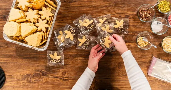 stock image Carefully packaging Christmas cutout cookies, half-dipped in chocolate, sprinkled with crushed nuts, and presented in clear cellophane wrapping.