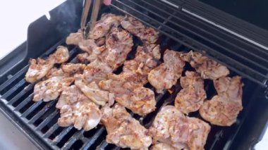 Salamura edilmiş tavuk butları küçük bir Weber ızgarasının ızgarasında cızırdar, havayı iştah açıcı bir koku ve hafif bir dumanla doldurur..