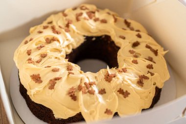 Tuzlu karamel şekerlemeleri ve zencefilli ekmek parçacıklarıyla süslenmiş zencefilli keki dikkatlice hediye etmek için açık pencereli beyaz bir kağıt bohça kek kutusuna yerleştiriyorum..