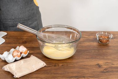 Bardak karıştırma kabında, büyük bir el çırpma ustalıkla lezzetli zencefilli kek ve karamel kremalı pasta malzemelerini karıştırır..