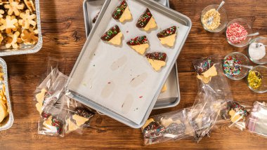 Dikkatlice paketlenmiş Noel kurabiyeleri, çikolataya batırılmış ve şeffaf selofan ambalajla sunulmuş, bayram hediyesi olarak mükemmel..