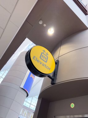 Denver, Colorado, ABD-15 Ağustos 2024, Denver Uluslararası Havaalanı DIA terminalinde bulunan parlak sarı asansör işaretinin yakın çekim görüntüsü. İşaret kolaylıkla görülebilir, yolculara yol gösterir.