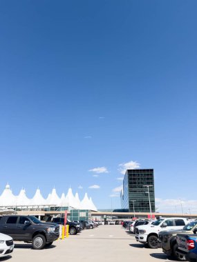 Denver, Colorado, ABD-15 Ağustos 2024 - Aydınlık bir günde Denver Uluslararası Havaalanı DIA 'nın otoparkının manzarası. Terminalin ikonik beyaz çadırlı çatısı ve cam yapısı...